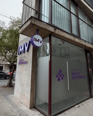 Entrada de IMV La Plata 2, con fachada gris y carteles violetas